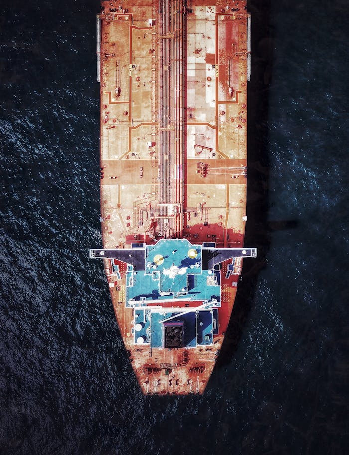 Top-down aerial photo of a large cargo ship navigating the open sea, highlighting the vessel's deck.